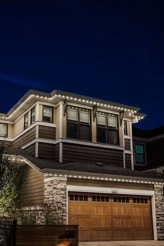 Contemporary two-story house with gemstone accent lighting along the roofline at night