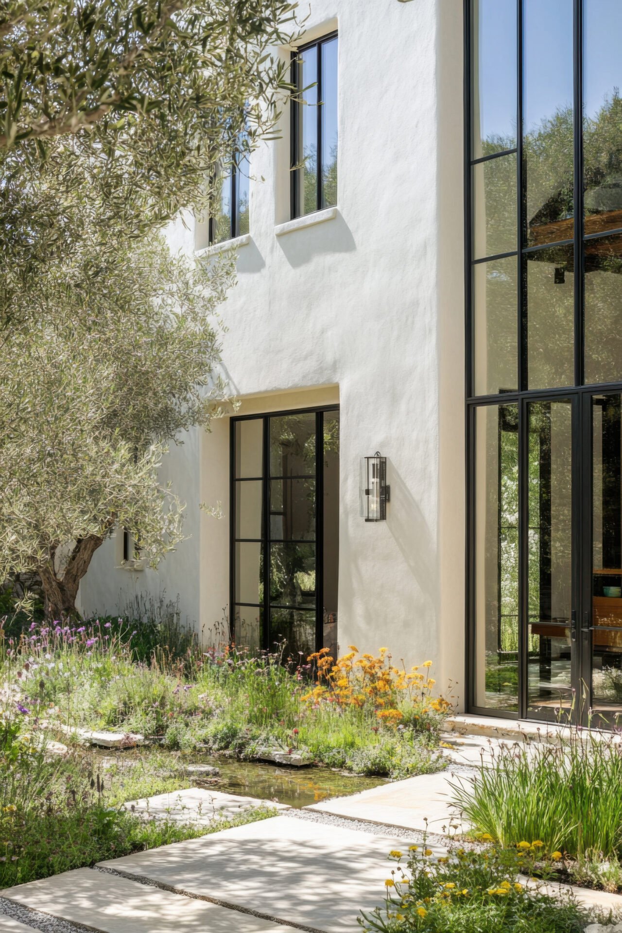 Modern white stucco home exterior with large windows and landscaped garden