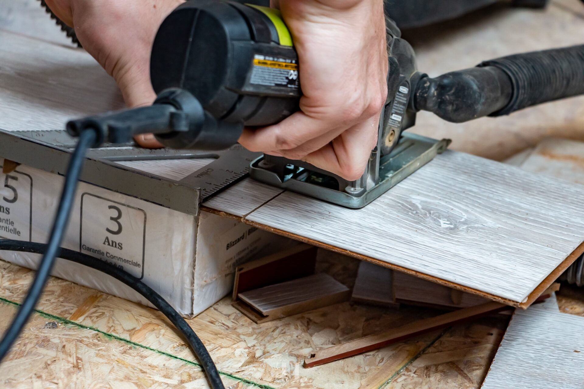 Close-up of hands using a saw to cut laminate flooring planks during installation
