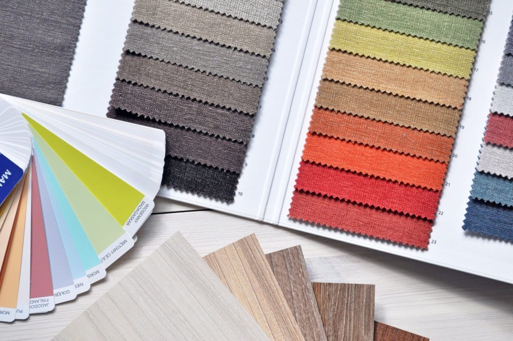 Variety of flooring, carpet, and paint samples arranged in a fan on a white table