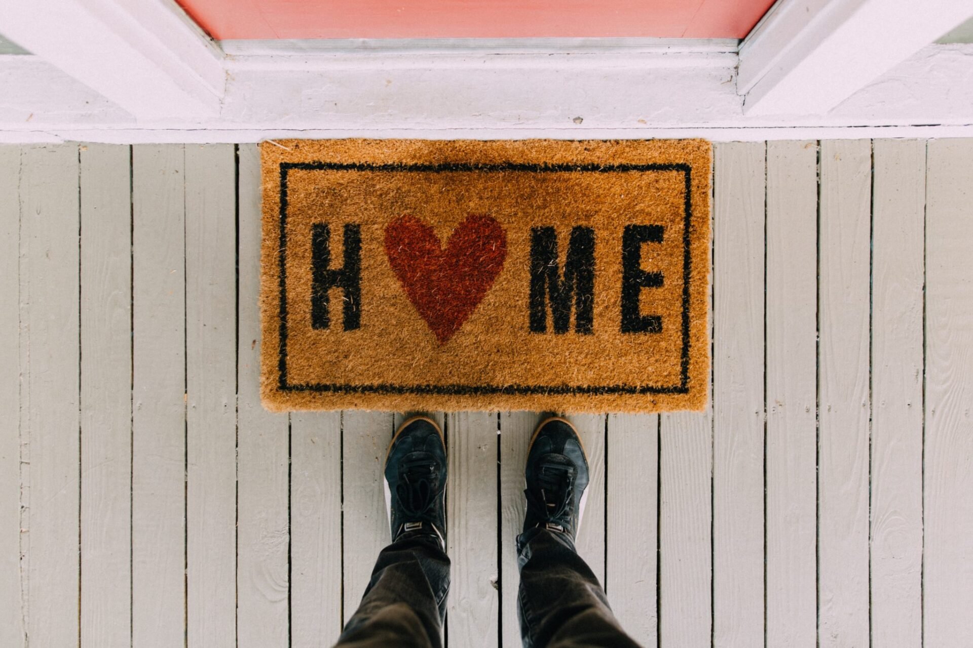 Welcome mat with the word "HOME" and two feet standing on a striped porch