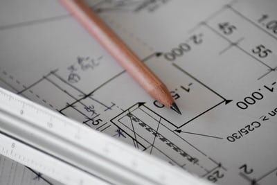 Person's hand drawing on a home floorplan with a pen, planning lighting layout