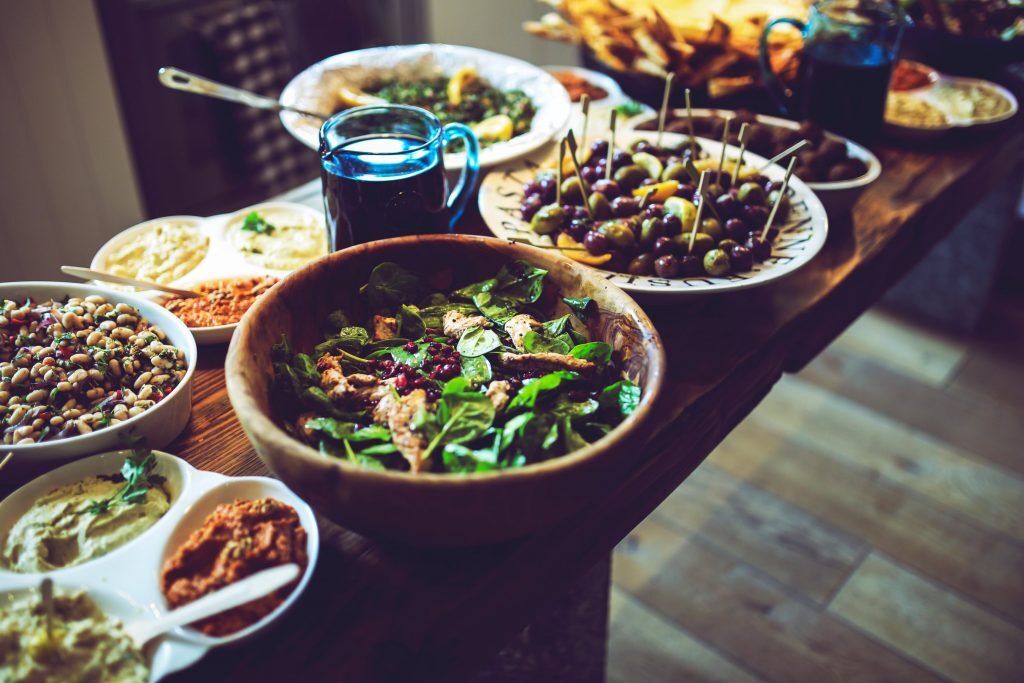 Table filled with a variety of holiday dishes, salads, and appetizers arranged for a festive meal
