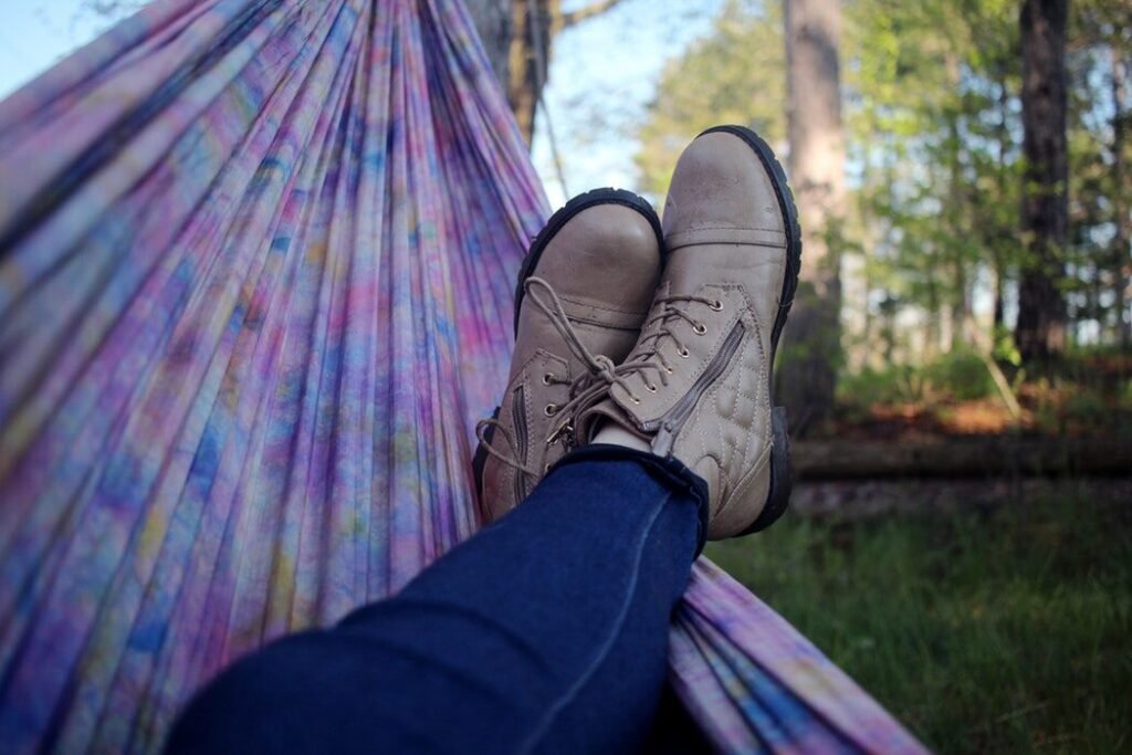 Person relaxing on a colorful hammock outdoors with feet up, enjoying a sunny day in the backyard